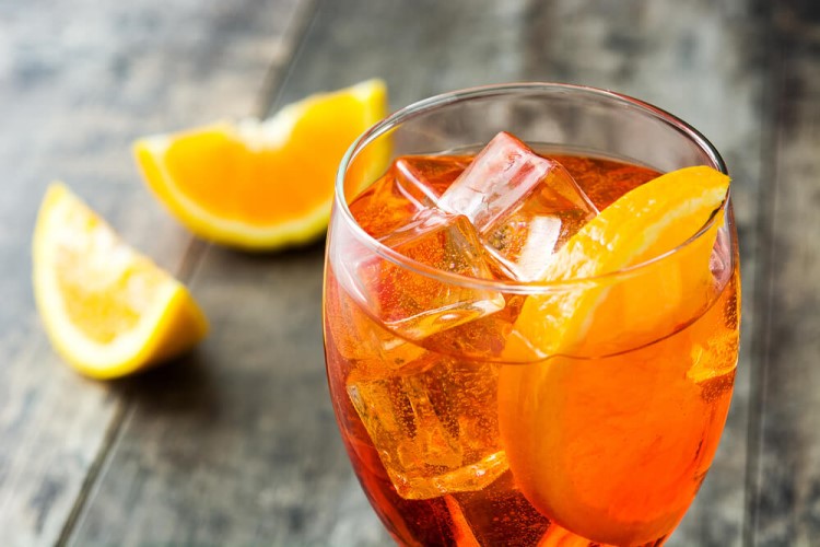 Drink London Spritz com gin, aperol, gelo e rodelas de limão.