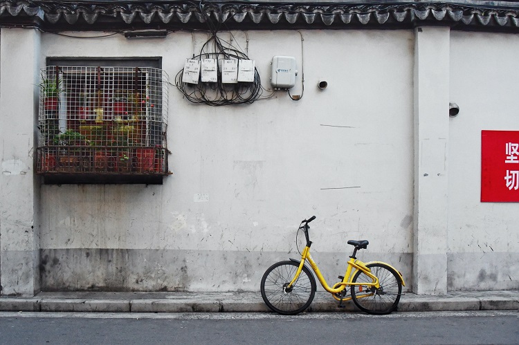 Bicicleta amarela encostada em um meio fio.