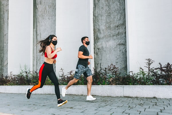 dupla de corredores correndo ao ar livre com máscara de proteção