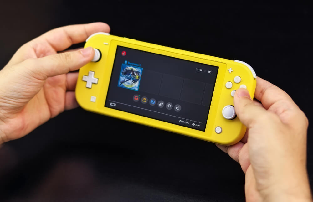 Nintendo Siwtch Lite amarelo nas mãos de uma pessoa.