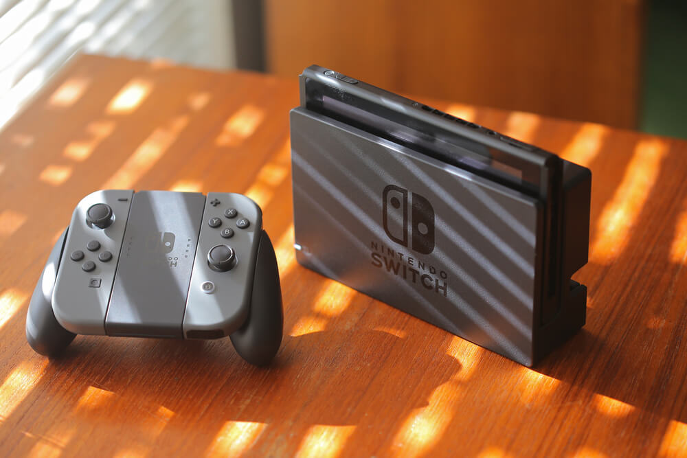 Nintendo Switch na cor cinza com controle ao lado sobre a mesa.