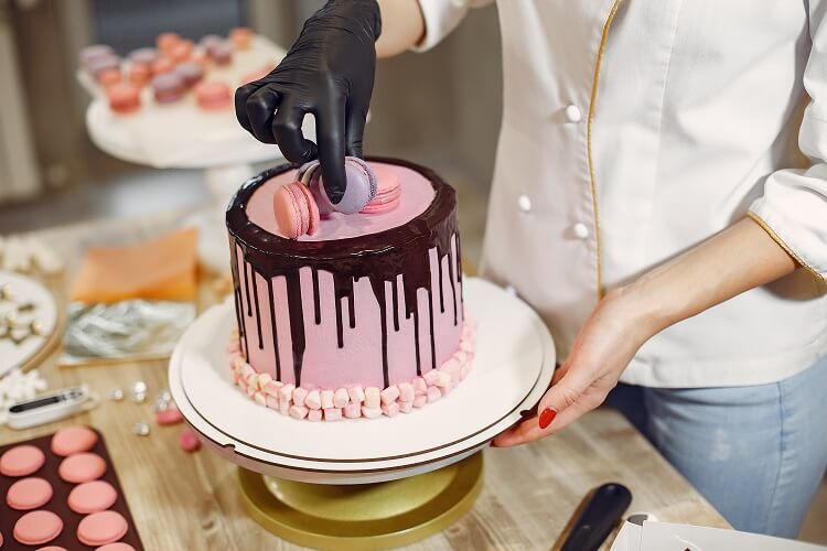 Mulher colocando macarron em um bolo