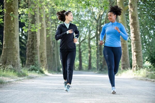 duas mulheres correndo em um parque usando roupas de corrida feminina, com calça, jaqueta e camiseta de manga longa