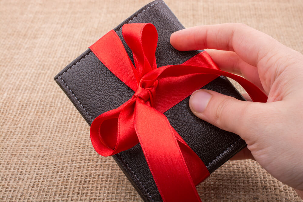 Imagem de uma carteira preta com um laço de fita vermelho.