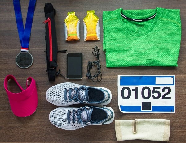 kit de prova de corrida de rua com gel de carboidrato, tênis, número de prova, medalha, viseira rosa e camiseta verde