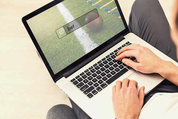 Homem utilizando um notebook para navegar na internet em busca dos melhores sites de apostas esportivas.