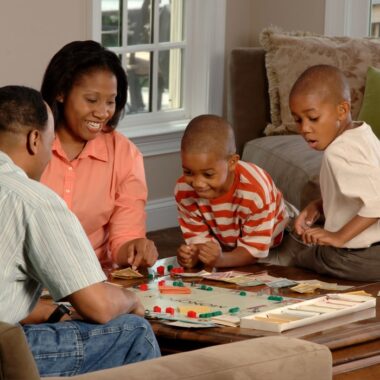 Pessoas negras brincando com jogos de tabuleiro para família.