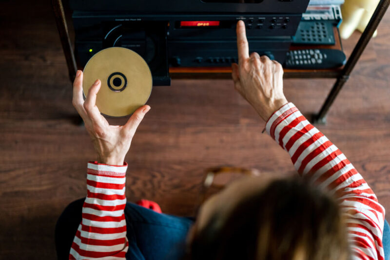 Mulher ligando rádio, enquanto segura um CD na outra mão.