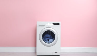 Máquina de lavar roupas em frente de parede rosa.