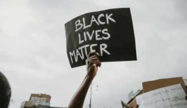Mão segurando um cartaz escrito "black lives matter" (vidas negras importam, em inglês).