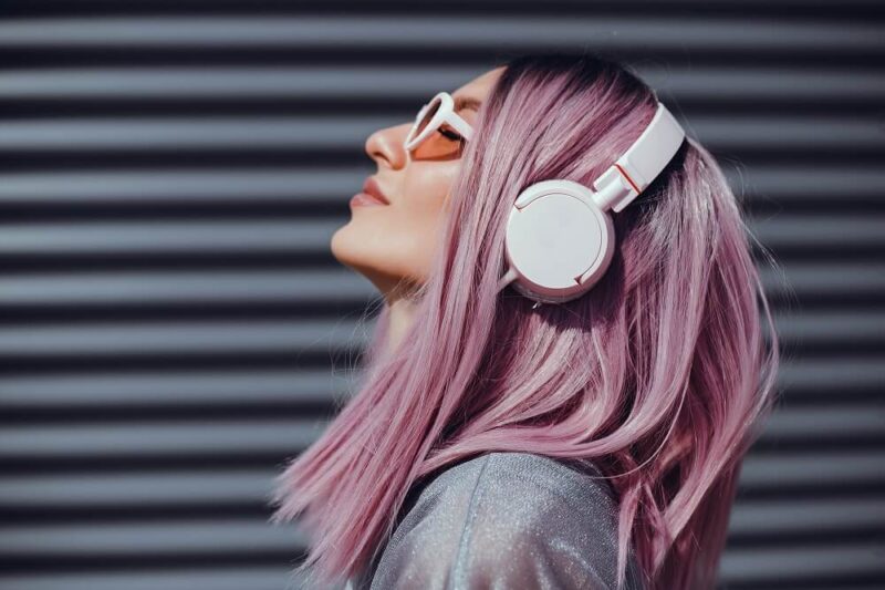 Mulher de cabelo rosa escutando música com headphones