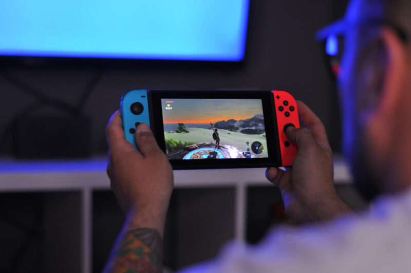 Pessoa jogando Nintendo Switch nas cores azul e vermelha.