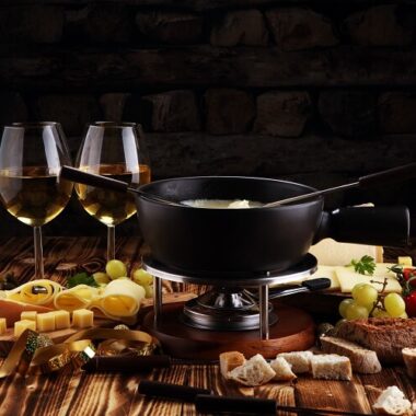 Panela de fondue com vinhos, queijos e outras guloseimas na mesa