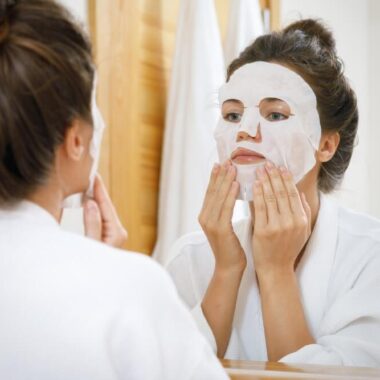 Mulher aplicando sheet mask no rosto