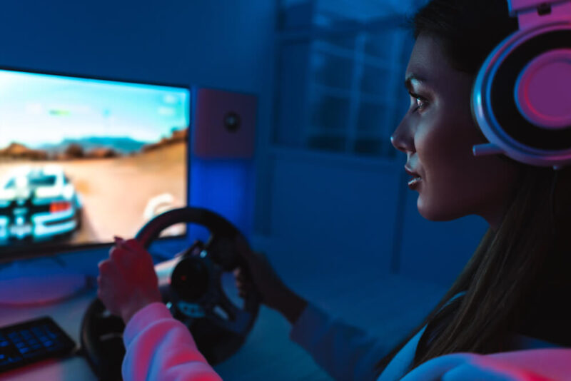 Mulher jogando utilizando o volante g920 com câmbio.