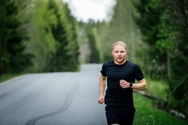 homem branco e loiro usando roupas pretas, correndo no asfalto com o relógio gps polar vantage v2