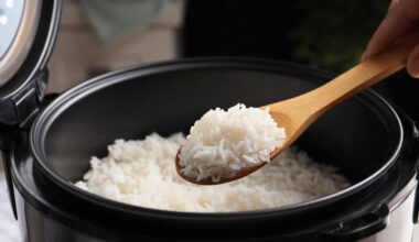 Colher de pau com arroz retirado de panela de arroz