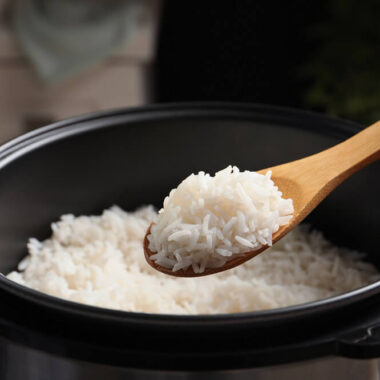 Colher de pau com arroz retirado de panela de arroz