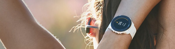 Mulher de costas com fone de ouvido e relógio Garmin 245 Music com pulseira branca no pulso. 