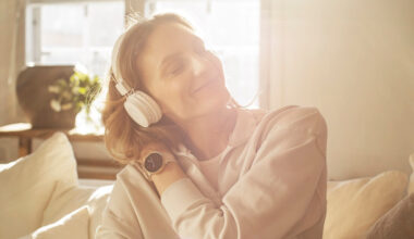 Mulher ouvindo música com headphone e com relógio Polar Ignite 2 no pulso esquerdo.