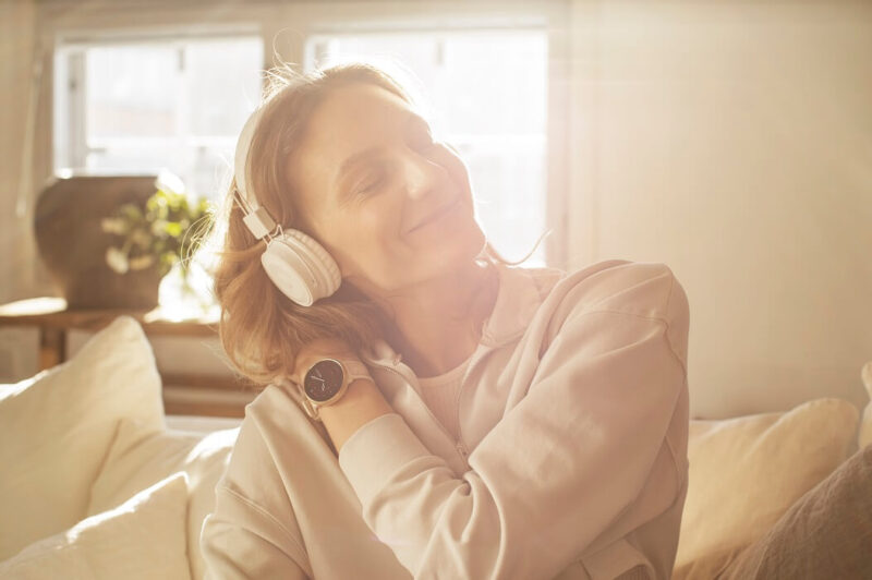 Mulher ouvindo música com headphone e com relógio Polar Ignite 2 no pulso esquerdo.