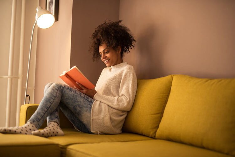 mulher sentada no sofá lendo um livro