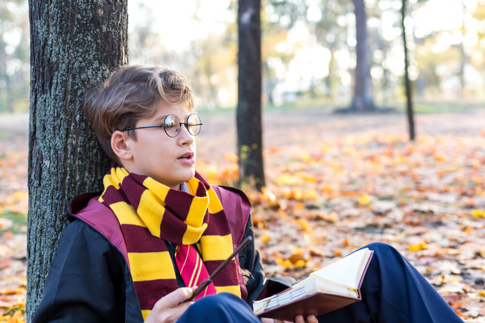 Imagem de um menino vestido com trajes que remetem a saga Harry Potter.