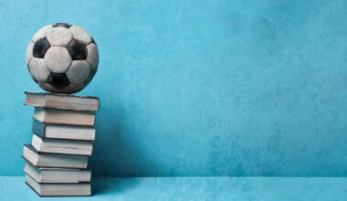 Livros sobre futebol - bola de futebol sobre uma pilha de livros, num fundo azul.