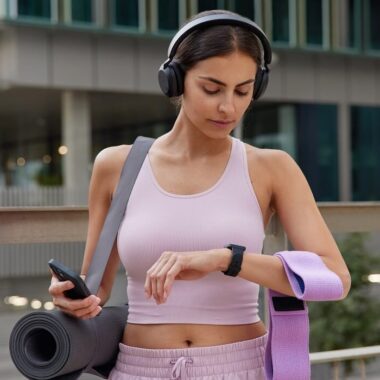 Mulher com acessórios e roupa de ioga olhando para smartwatch.