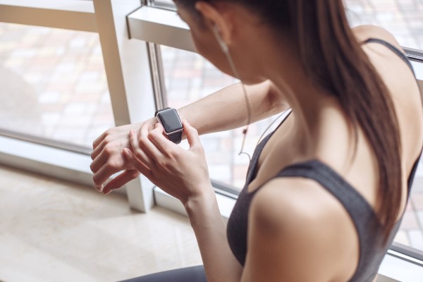 Mulher mexendo em seu smartwatch antes de realizar exercício físico.