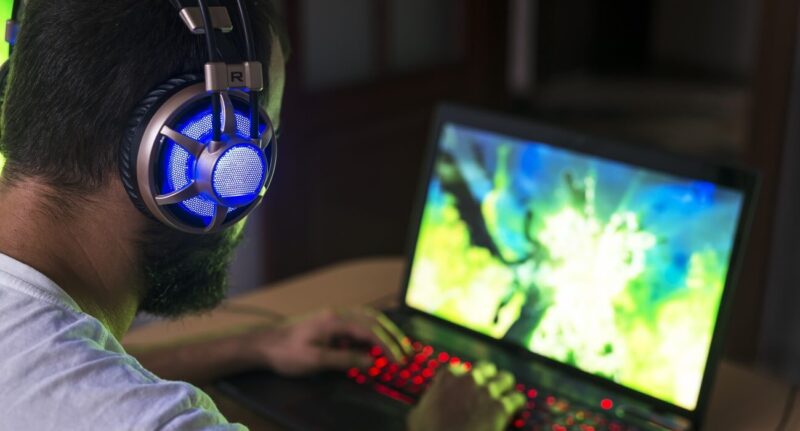 Homem com headset jogando em seu notebook gamer.