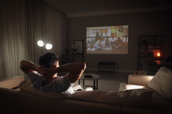 Homem assiste a filme sozinho em sua sala de cinema em casa.